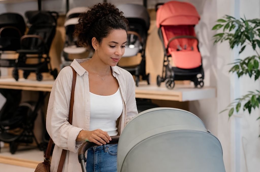 Comment choisir sa poussette : jeune maman métisse dans un magasin de puériculture