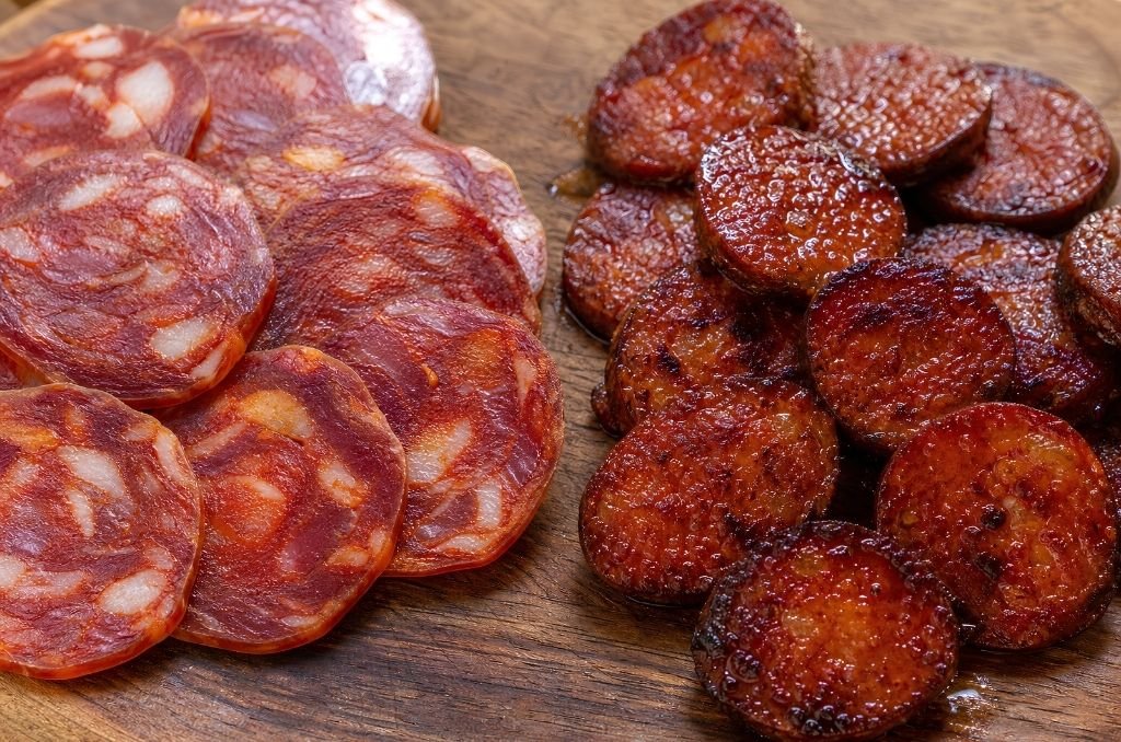 Chorizo cru séché et chorizo cuit à la poêle côte à côte sur une planche en bois