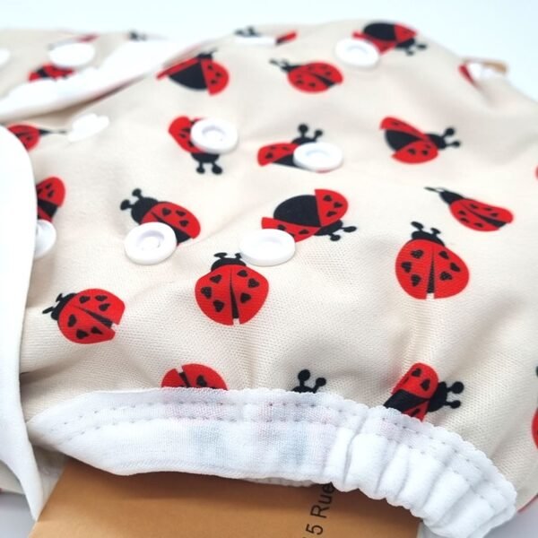 Détail du tissu et des pressions de la couche lavable B'bies motif coccinelles Détail du tissu et des pressions de la couche lavable B'bies motif coccinelles