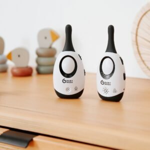 Les deux unités de l'écoute-bébé Babymoov Simply Care posées sur une commode en bois, à côté de jouets