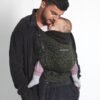 HoodieCarrier 2 Love Radius en portage ventral Homme portant un bébé endormi sur le ventre dans le porte-bébé HoodieCarrier 2 Love Radius wild camo