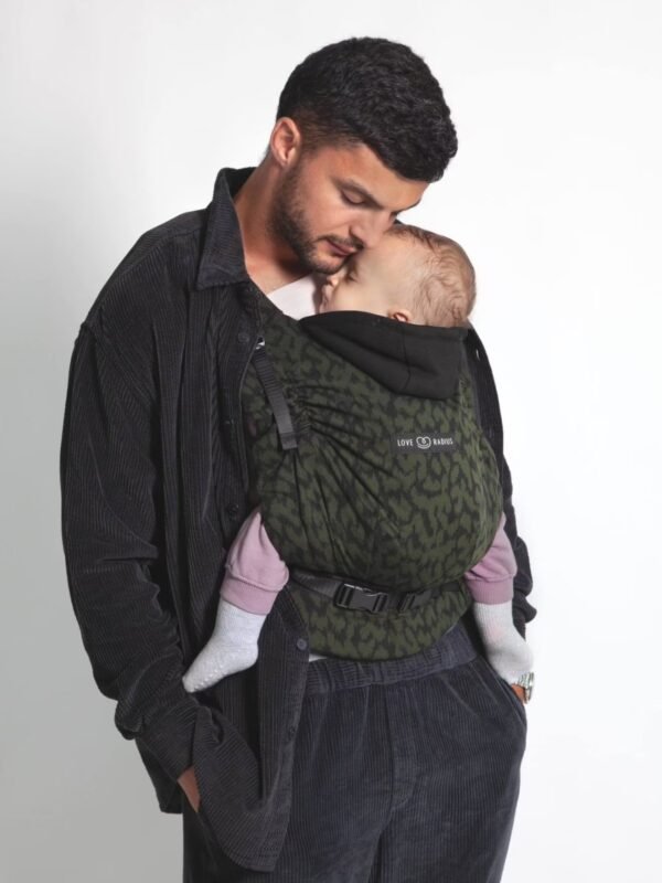 HoodieCarrier 2 Love Radius en portage ventral Homme portant un bébé endormi sur le ventre dans le porte-bébé HoodieCarrier 2 Love Radius wild camo