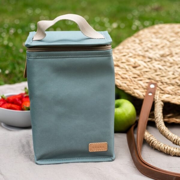 Sac isotherme Béaba vert sauge en extérieur Sac isotherme Béaba vert sauge fermé, posé sur une nappe de pique-nique