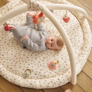 Bébé allongé sur le dos sur le tapis d'éveil Cocotte Vertbaudet, sous deux arches à jouets suspendus
