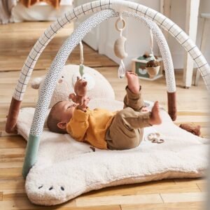 Bébé allongé sur le dos sous l'arche du tapis d'éveil Green Forest Vertbaudet, jouets suspendus au-dessus de lui