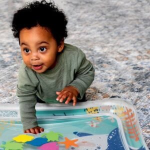 Bébé à plat ventre sur un tapis d'eau gonflable transparent, décoré de motifs marins colorés