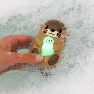 Petite lampe de bain en forme d'otarie tenue au-dessus de l'eau, lumière verte allumée